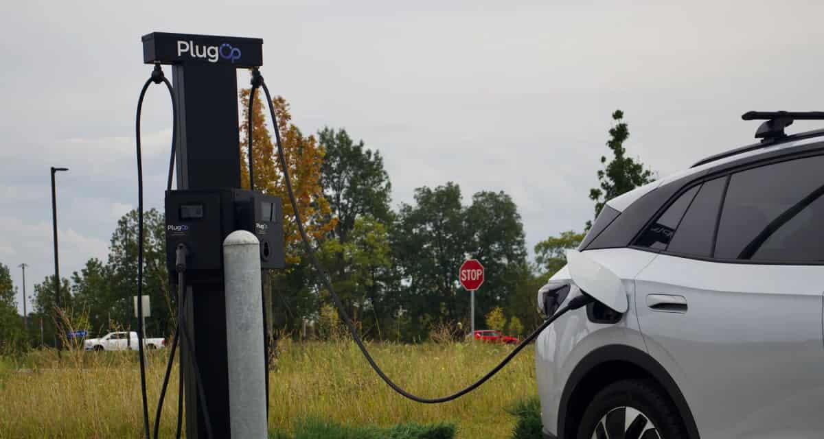 PlugOp Level 2 charging station with its cable plugged into a white electric SUV