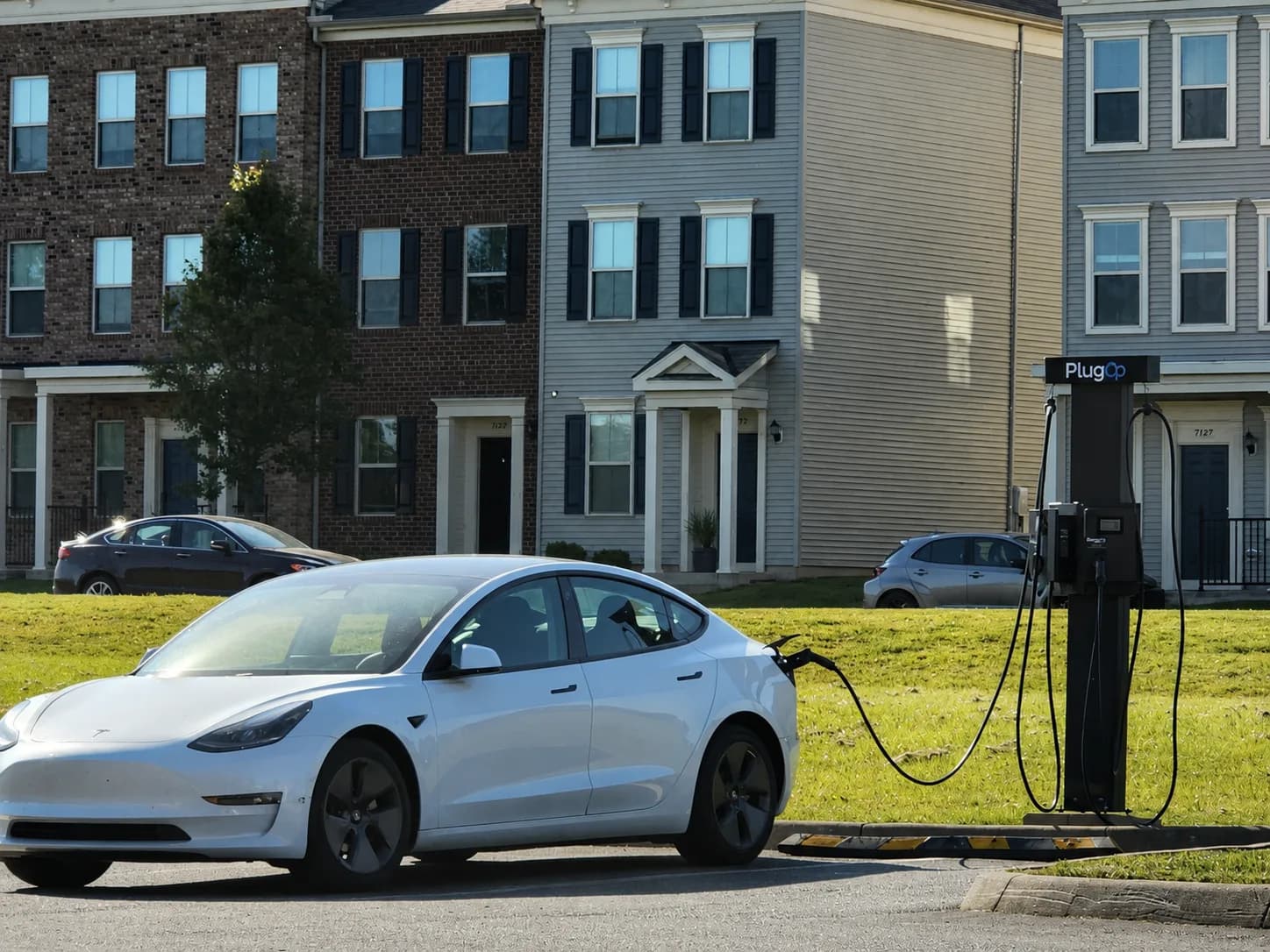 Resident EV charging beside a PlugOp charger at a townhome community